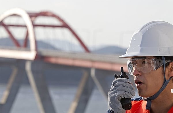 Field worker uses a TETRA radio near a bridge