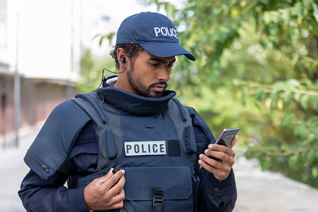 Police-officer-looks-at-his-smartphone-640px-wide