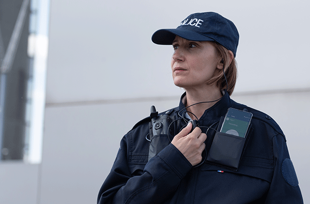 Police woman using a TETRA radio and a smartphone