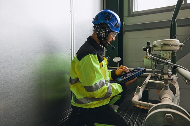 Worker-with-smart-device-next-to-factory-equipment-640px-wide