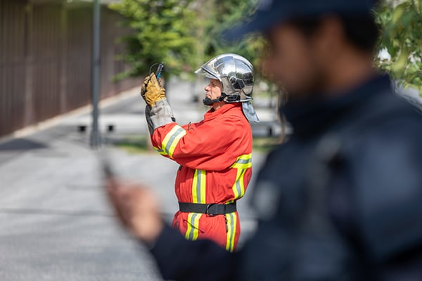 Fireman is taking a photo, a police out of focus is on the foreground