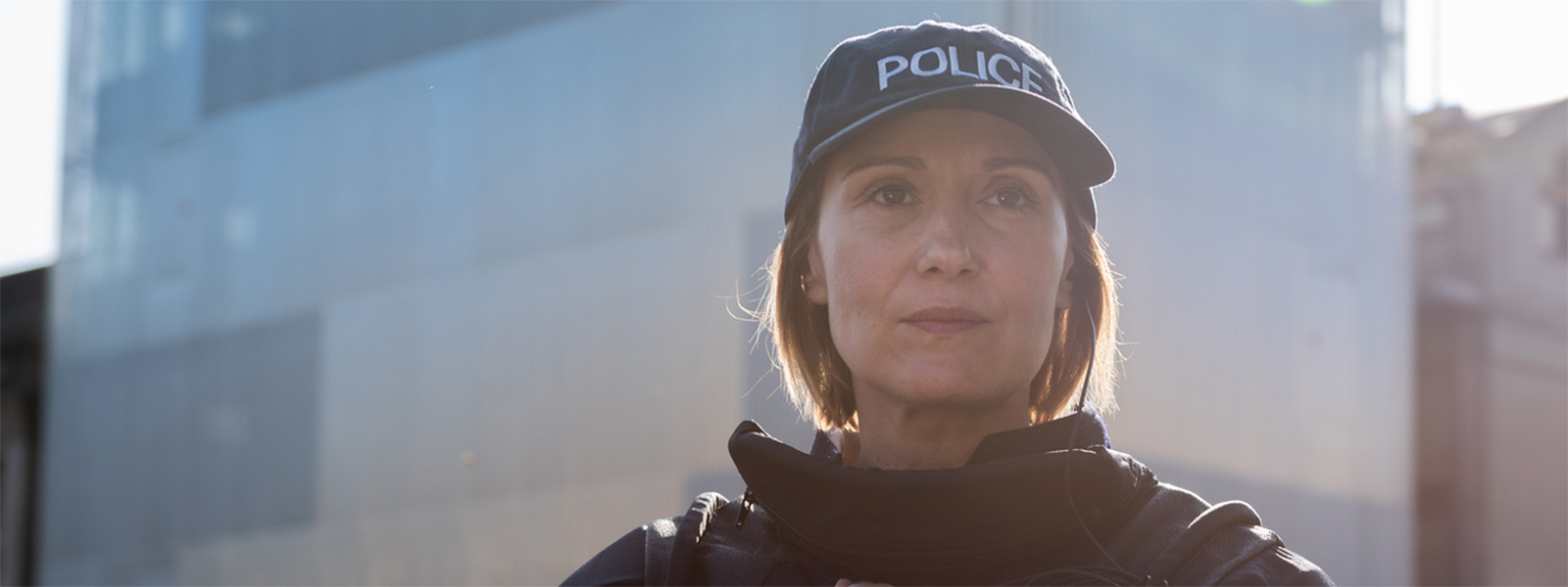 Female-police-officer-in-front-of-a-building-1600x600